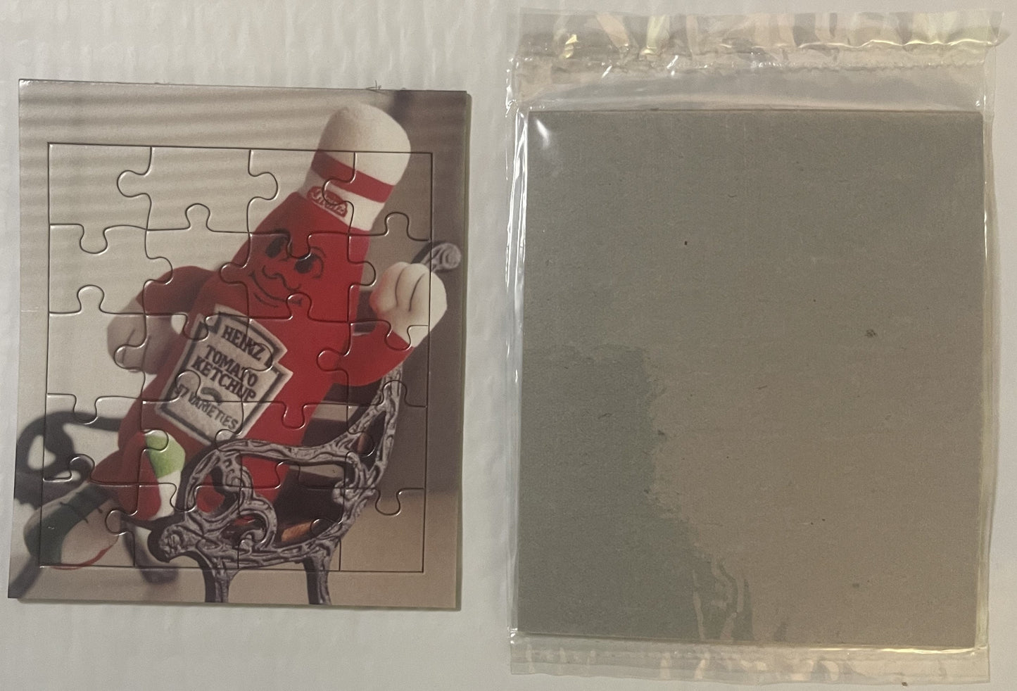 Vintage Heinz ketchup mascot puzzle showing red-suited character with striped hat, displayed next to clear plastic packaging 