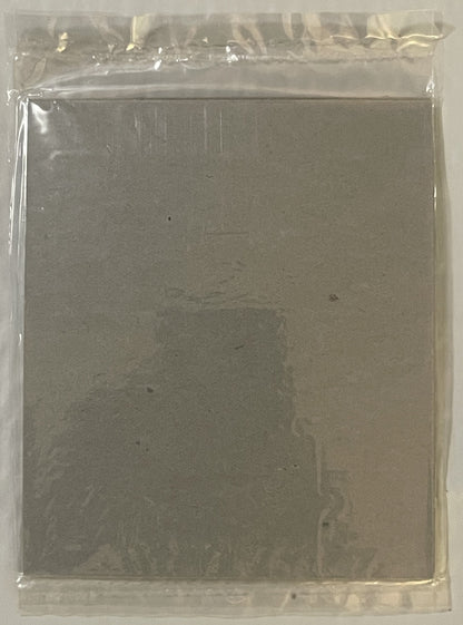 Sealed plastic package containing a grey cardboard puzzle box with faint printed text visible through the packaging