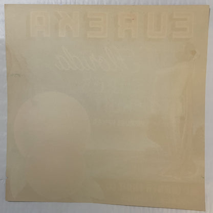 Cream-colored vintage citrus crate label with embossed text and faint Native American imagery, photographed flat against whit