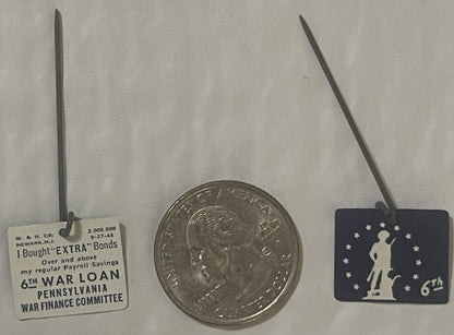 Three WWII-era badges displayed with a quarter for scale: cream tag reading "6TH WAR LOAN PENNSYLVANIA" on left, silver coin 