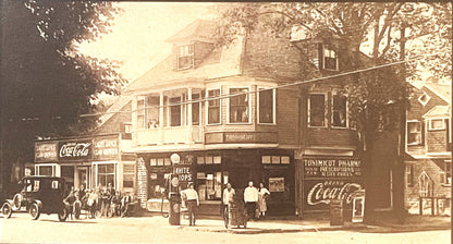 Sepia-toned vintage street scene showing storefront with "White Tops" and "Tonimicut Pharmacy" signs, Coca-Cola advertising, 