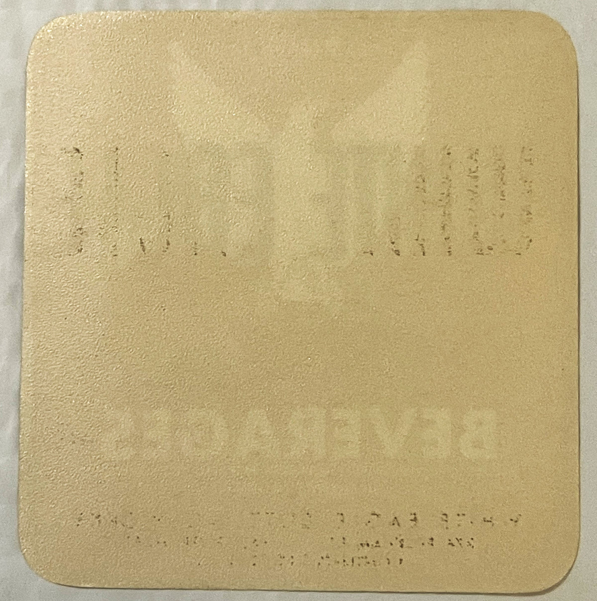 Cream-colored embossed label with faint printed text visible on surface, shown flat against white background