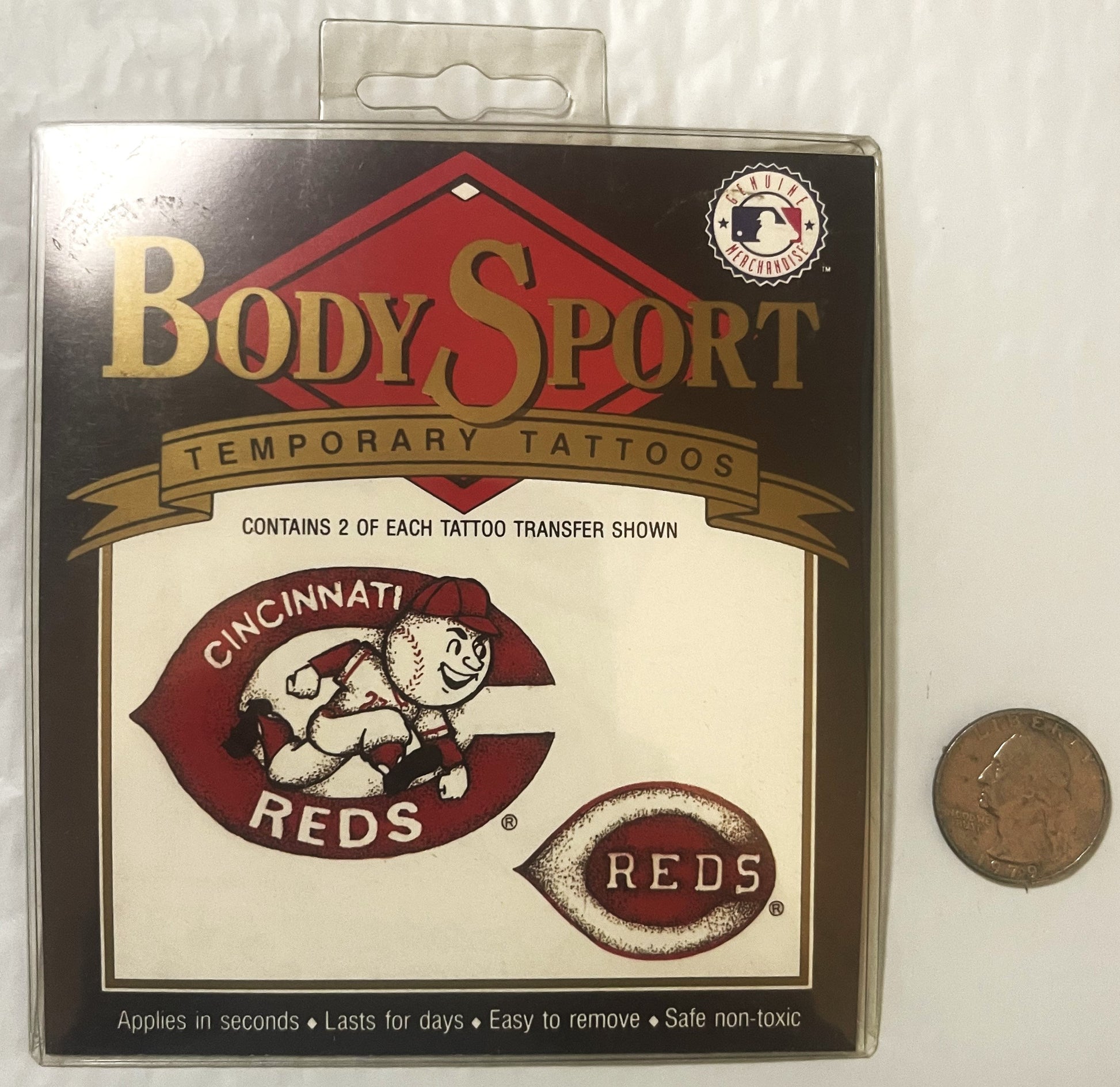 Sealed package of Body Sport temporary Cincinnati Reds tattoos featuring Mr. Red mascot logo, displayed next to a quarter for s