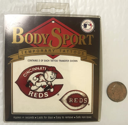 Sealed package of Body Sport temporary Cincinnati Reds tattoos featuring Mr. Red mascot logo, displayed next to a quarter for s