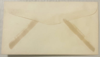 Cream-colored vintage envelope with embossed flap and faint impressions of text, photographed flat from above
