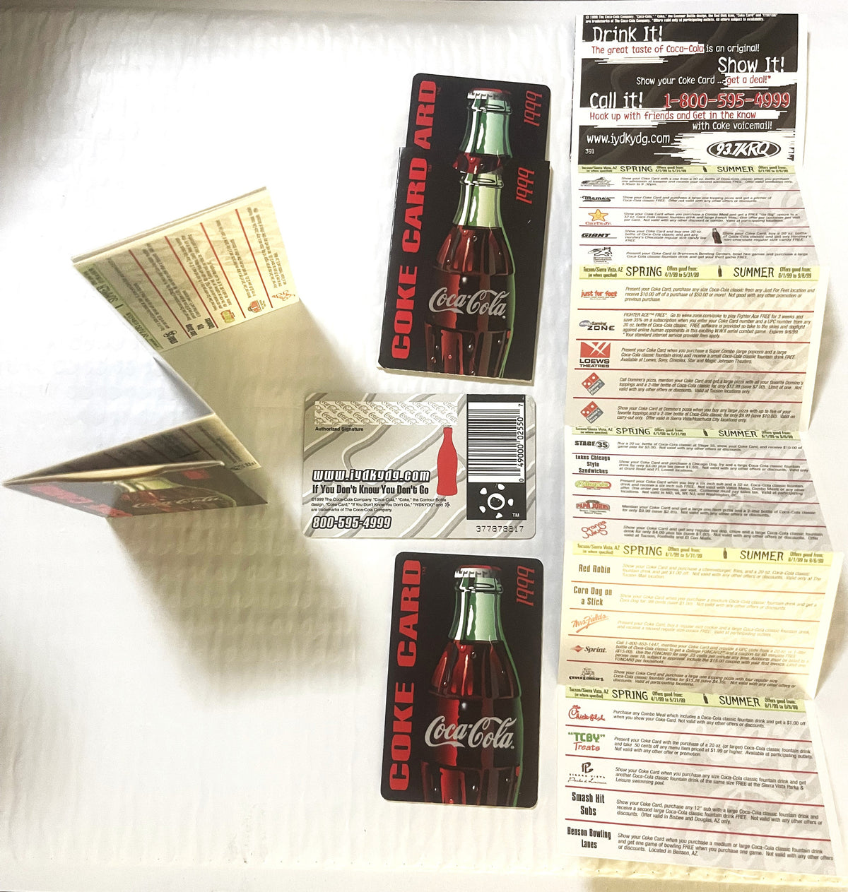 Vintage Coca-Cola promotional credit card with two bottle designs and accordion-fold coupon sheet displayed flat on white sur