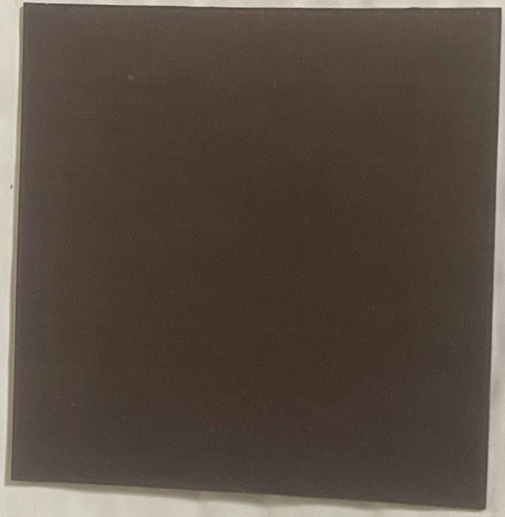Dark brown square refrigerator magnet photographed flat against white background, appears blank or unmarked on visible side