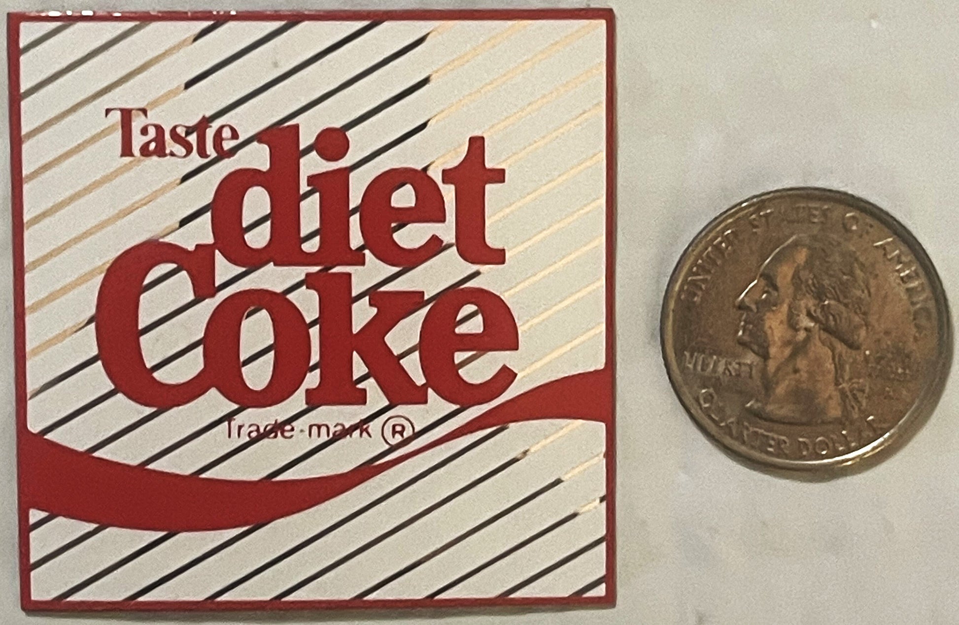 Vintage Diet Coke refrigerator magnet with red and cream diagonal stripe design, shown next to a quarter for scale.
