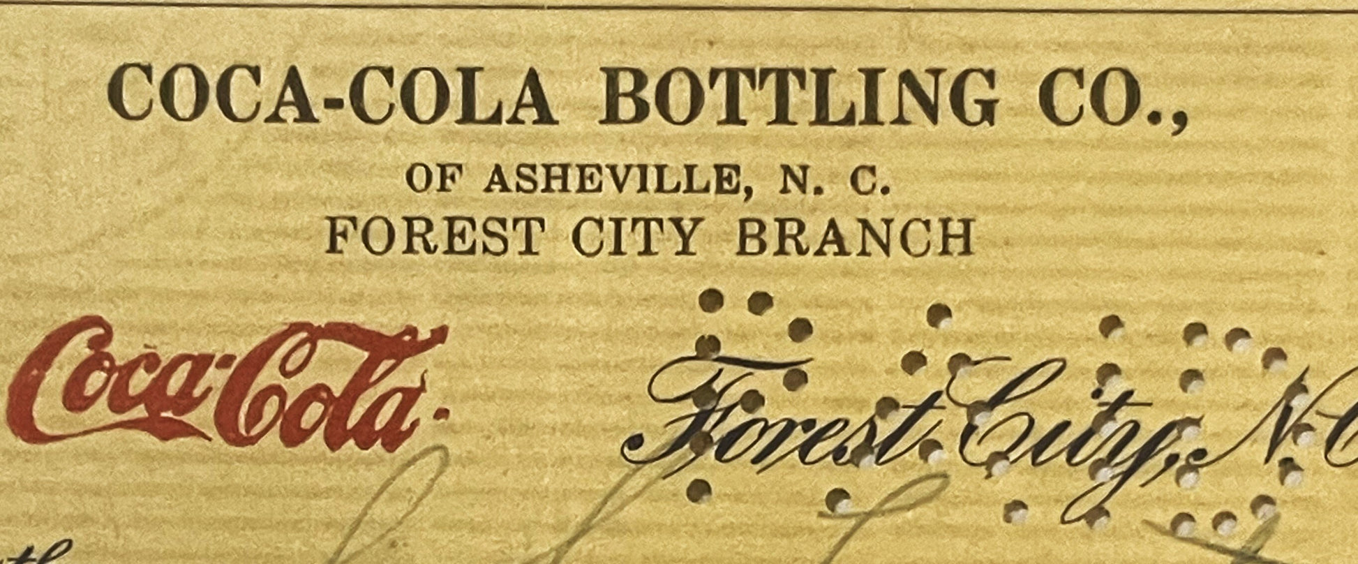 Top portion of aged bank check from Coca-Cola Bottling Co. of Asheville N.C. Forest City Branch, featuring red Coca-Cola scri