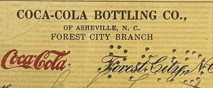 Top portion of aged bank check from Coca-Cola Bottling Co. of Asheville N.C. Forest City Branch, featuring red Coca-Cola scri