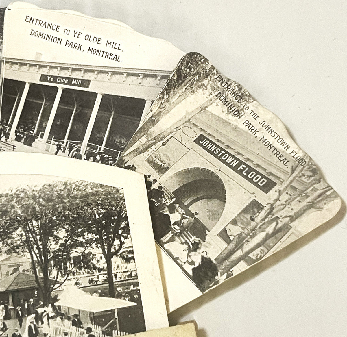 Overlapping vintage black and white postcards showing Montreal attractions including Ye Olde Mill, Johnstown Flood display, a