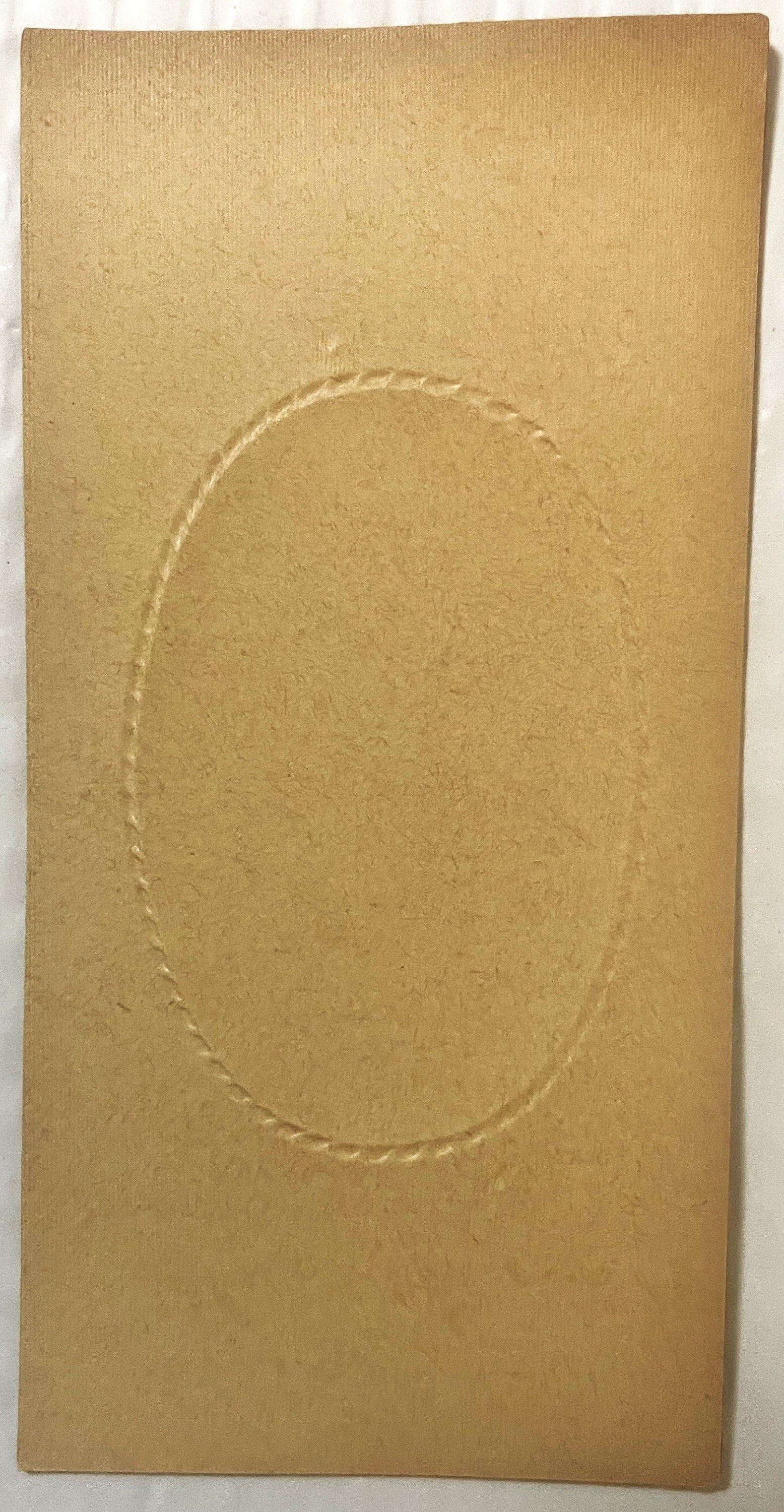 Tan cardboard box insert with embossed oval frame, photographed flat against white background