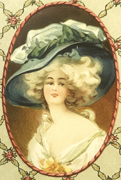 Chromolithograph portrait of a woman with blonde curled hair wearing a large blue hat with white plumes, framed by decorative