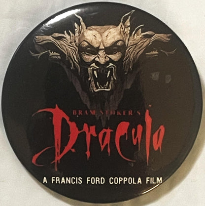 Round pin back button with black background, demonic face illustration in tan, red "Dracula" text, and white