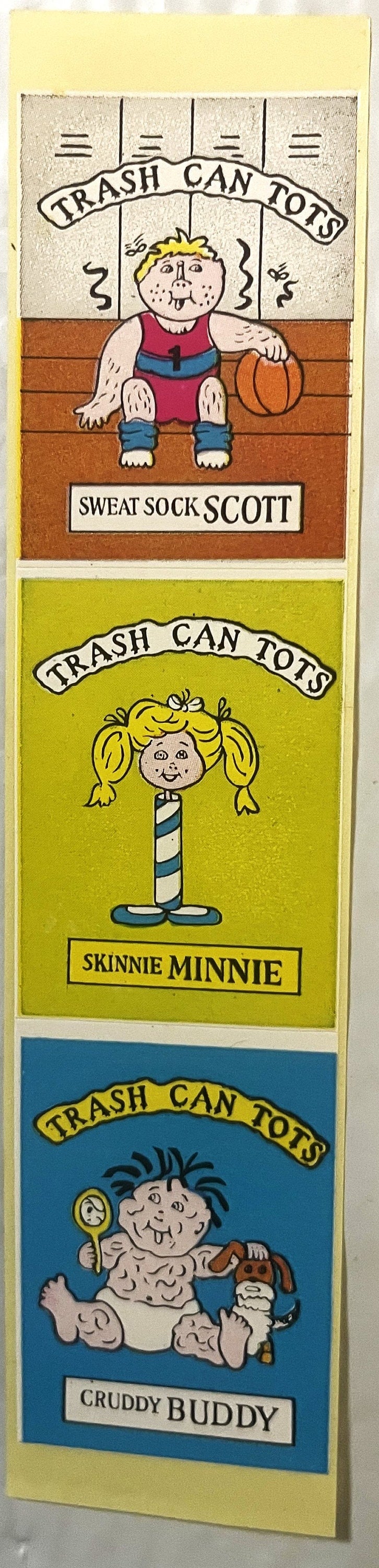 Three sticker panels showing cartoon characters labeled Sweat Sock Scott, Skinny Minnie, and Cruddy Buddy in "Trash Can Tots"