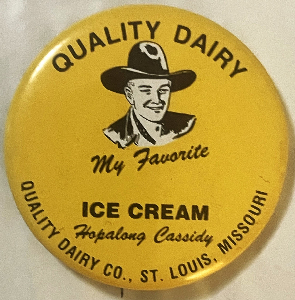 Yellow circular pin featuring a cowboy in black hat with "Quality Dairy Ice Cream My Favorite Hopalong Cassidy"