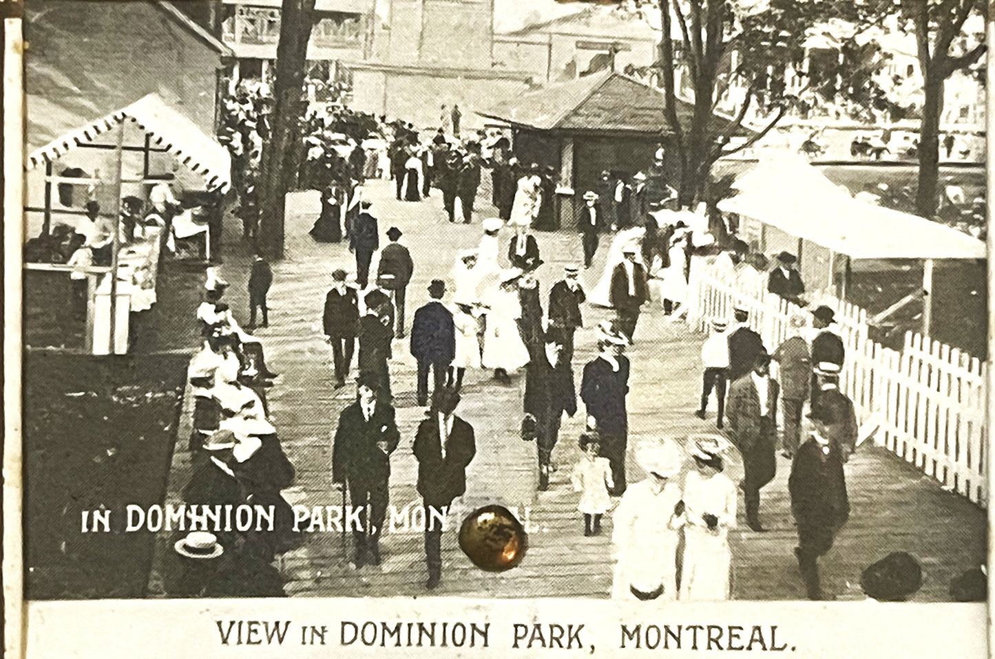 Sepia-toned postcard showing crowded boardwalk scene in Dominion Park, Montreal, with Victorian-era visitors in formal dress,