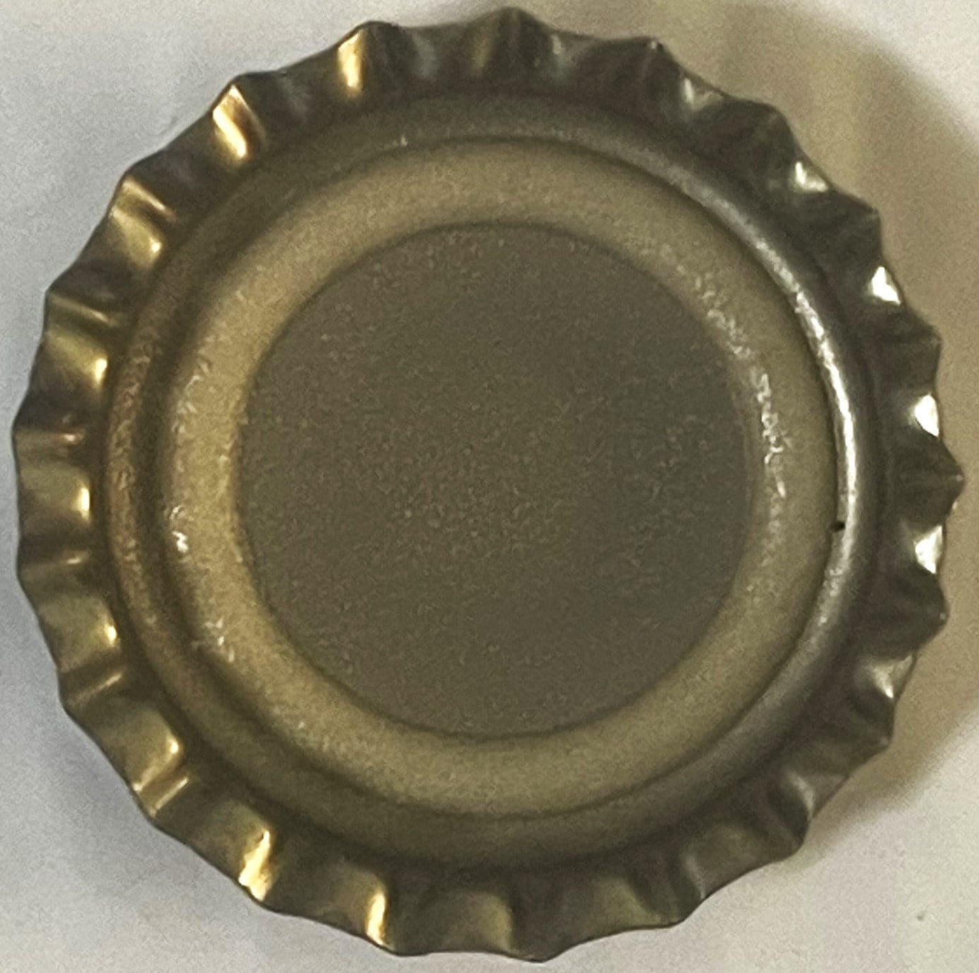 Vintage bottle cap with crimped metal edges and ribbed rim, shown from above on white surface
