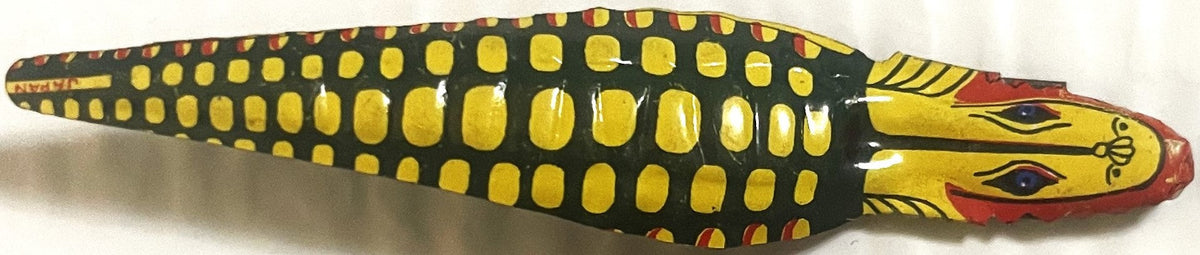 Vintage tin snake noisemaker with dark green body, yellow rounded spots, yellow head with red mouth and blue eyes, shown from
