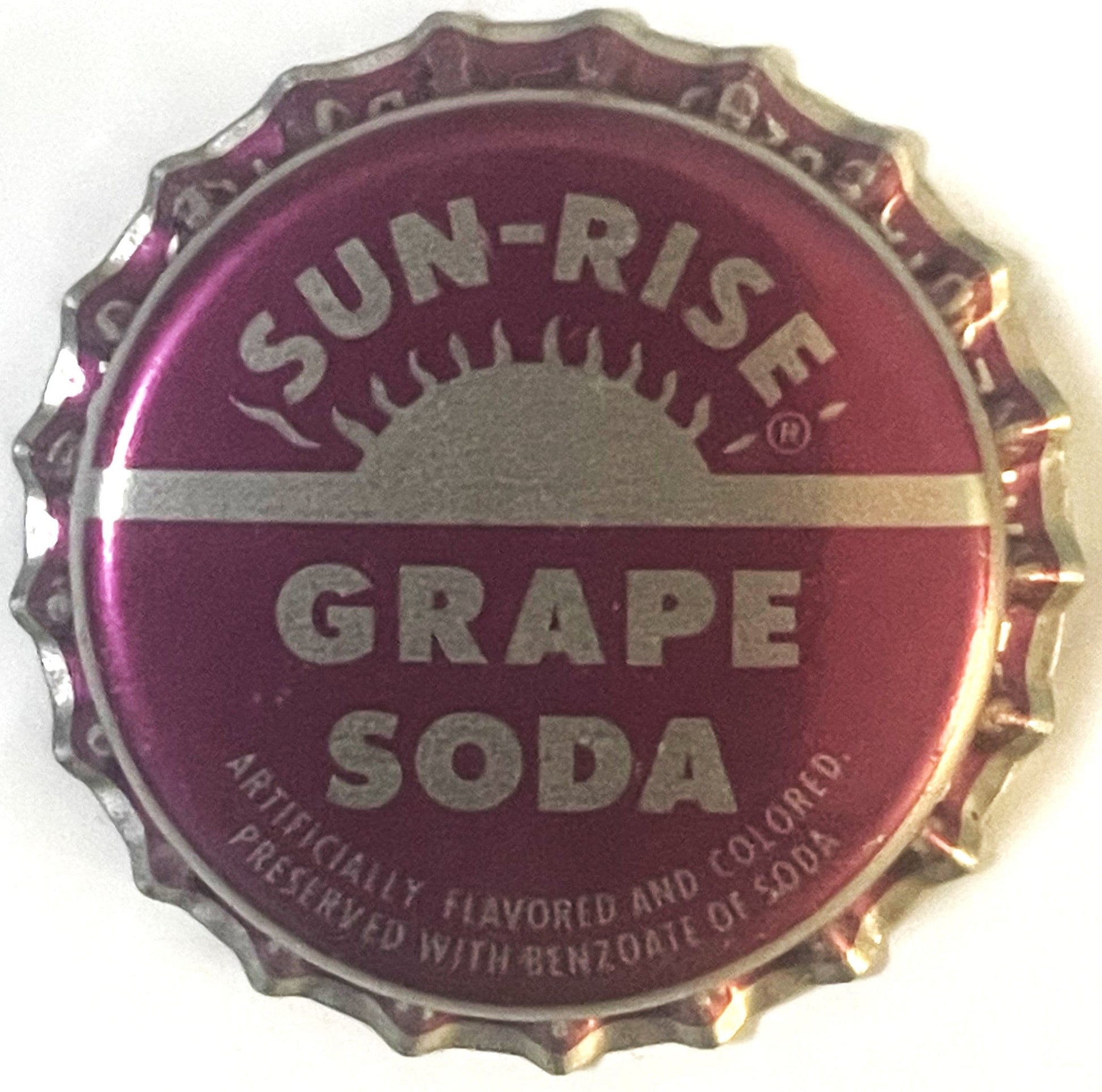 Purple bottle cap with "SUN-RISE GRAPE SODA" text and sun logo, shown flat against white background