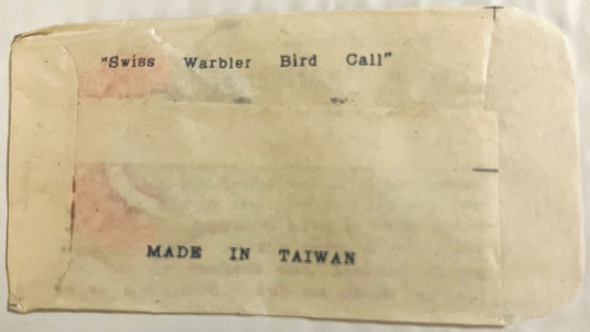 Cream-colored vintage box back with "Swiss Warbler Bird Call" and "Made in Taiwan" printed text, showing age discoloration an