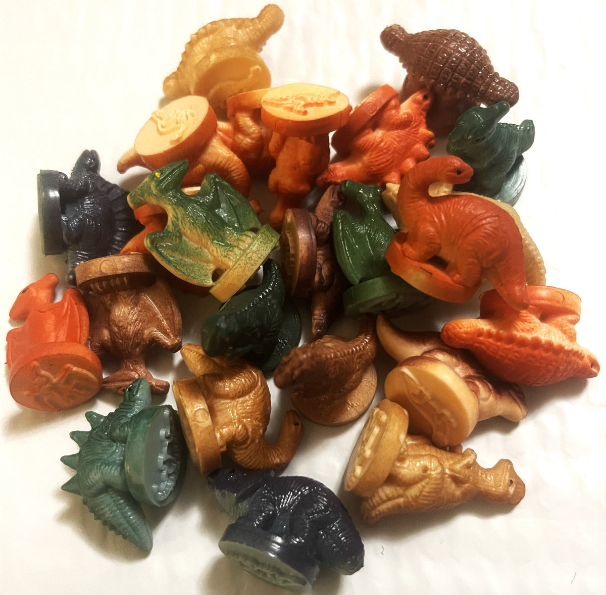 Colorful rubber dinosaur and animal stamps in orange, tan, brown, black and green arranged on white surface