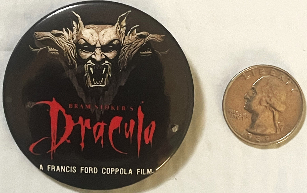 Vintage Dracula pin button with demon face artwork and red text, shown next to quarter for scale on white background