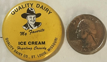 Yellow pin badge with cowboy illustration next to quarter coin for scale, text reads "Quality Dairy Ice Cream My Favorite Hop