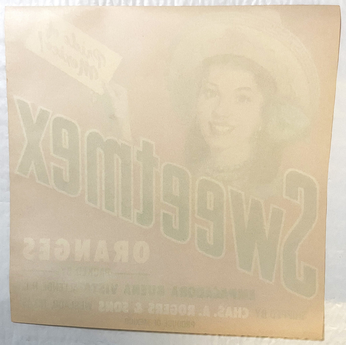Cream-colored vintage crate label with embossed "Sweetmex" text and portrait, angled view showing texture