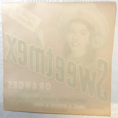 Cream-colored vintage crate label with embossed "Sweetmex" text and portrait, angled view showing texture