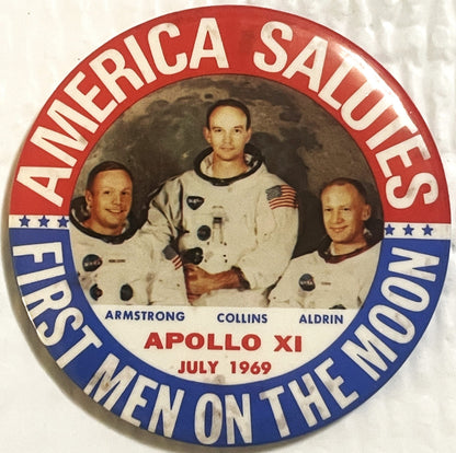 Front of the large 3.5 inch Apollo 11 pinback: the NASA crew portrait of Armstrong, Collins and Aldrin against a lunar backdrop, ringed by AMERICA SALUTES above and FIRST MEN ON THE MOON below, with APOLLO XI and JULY 1969 beneath the photograph.
