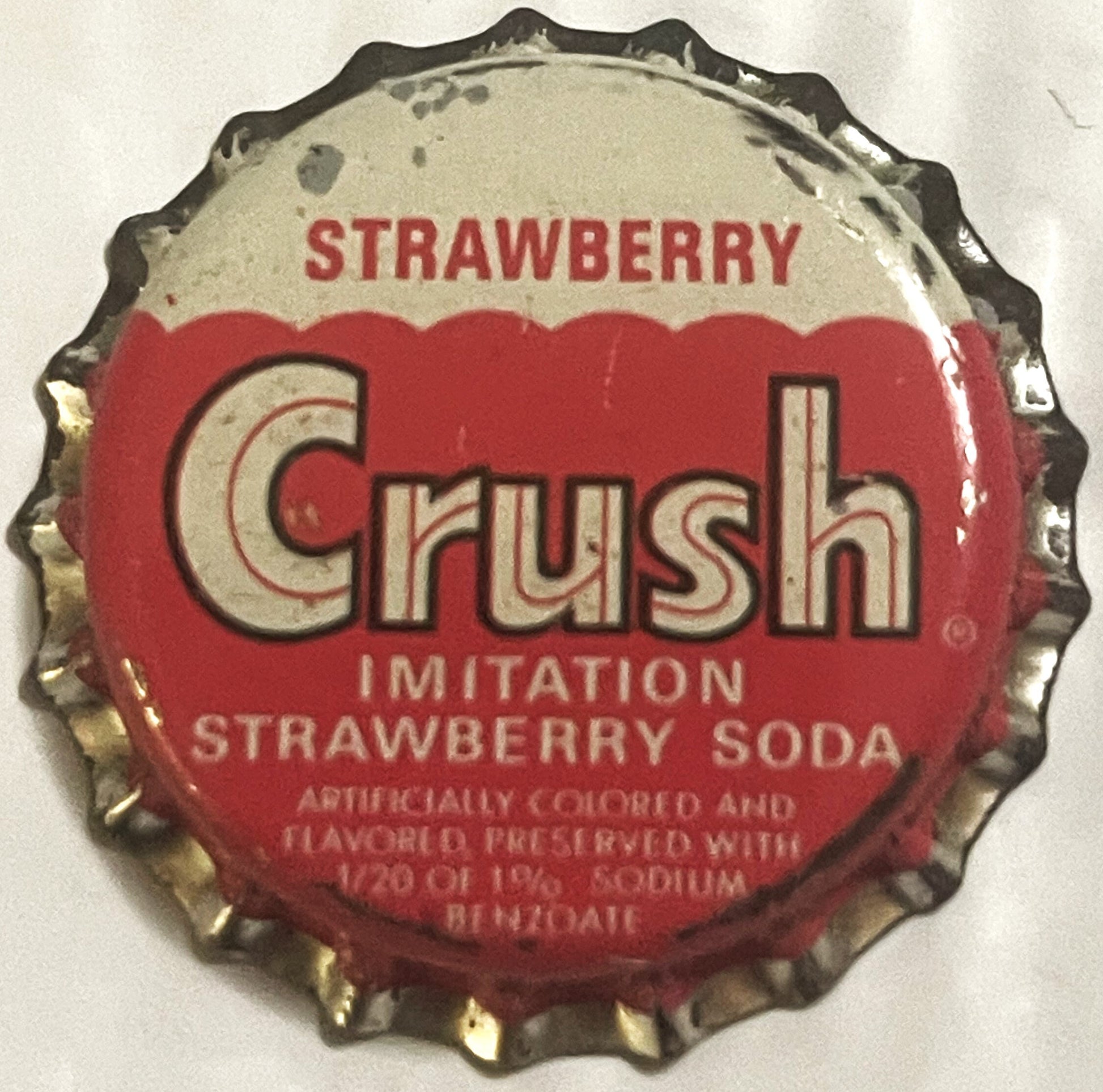 Vintage red and cream Strawberry Crush soda bottle cap with cork lining and crimped metal edges, shown flat from above.