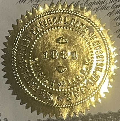 Gold embossed circular seal from vintage bank stock certificate with eagle, decorative border, and text reading " " and "H