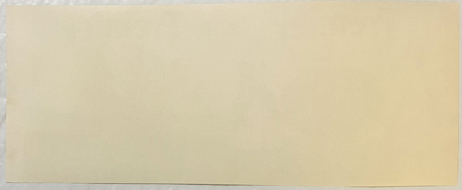 Blank cream-colored vintage label or packaging material with minimal visible text or design elements against plain background
