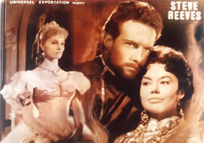 Vintage movie poster showing bearded man with two women in period costume against warm-toned background; "Steve Reeves" text 