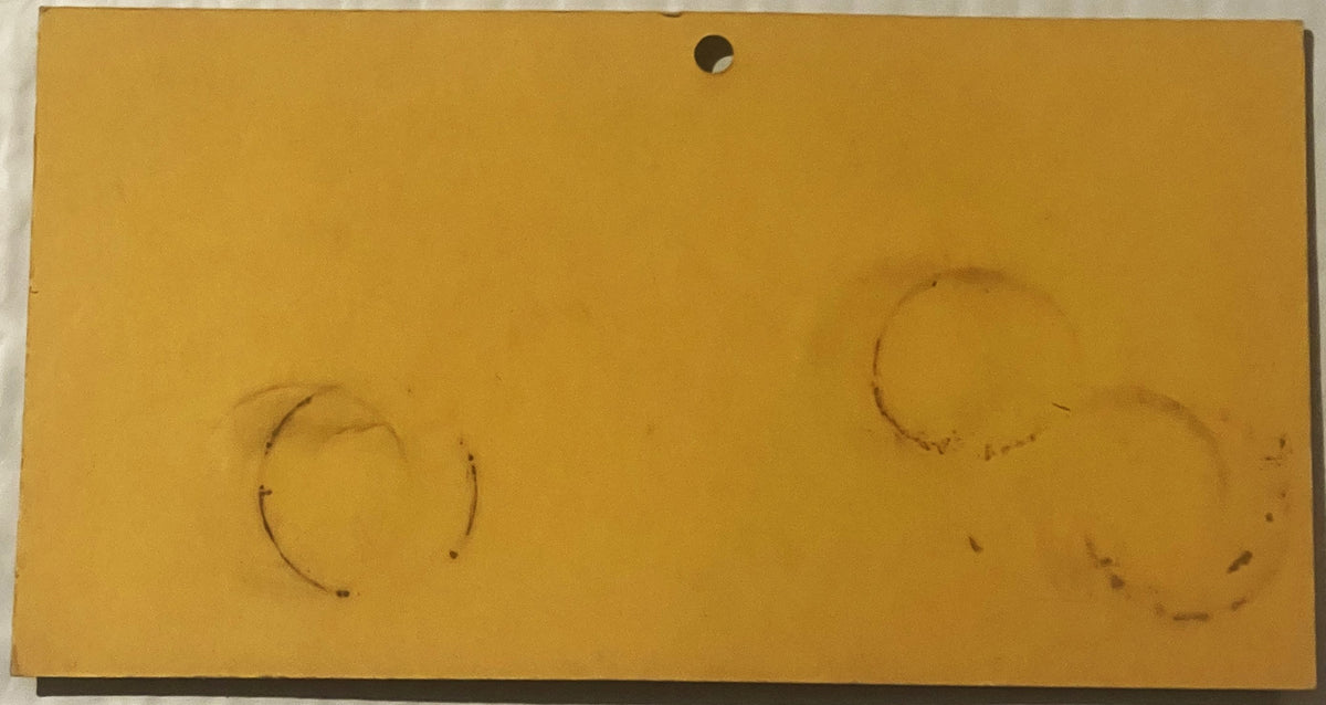 Faded yellow advertising card with two faint circular marks and a hole punched at top center