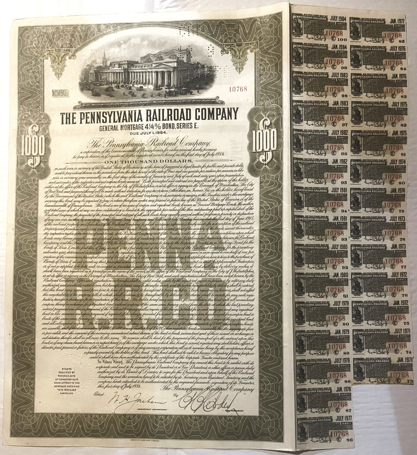 Vintage 1934 Pennsylvania Railroad $1000 bond certificate with attached coupon sheets showing dates from 1971-1984, displayed