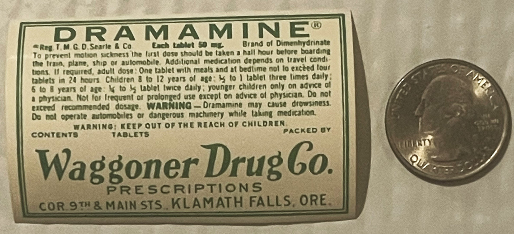 Vintage Dramamine tablet label from Waggoner Drug Co, Klamath Falls OR, next to a penny for scale