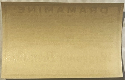 Cream-colored vintage Dramamine label on dark background, front view showing faded printing