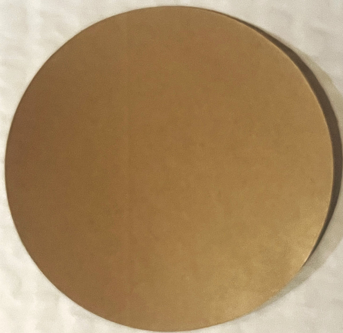 Tan circular sticker on white background, showing wear and age, mounted flat for photography