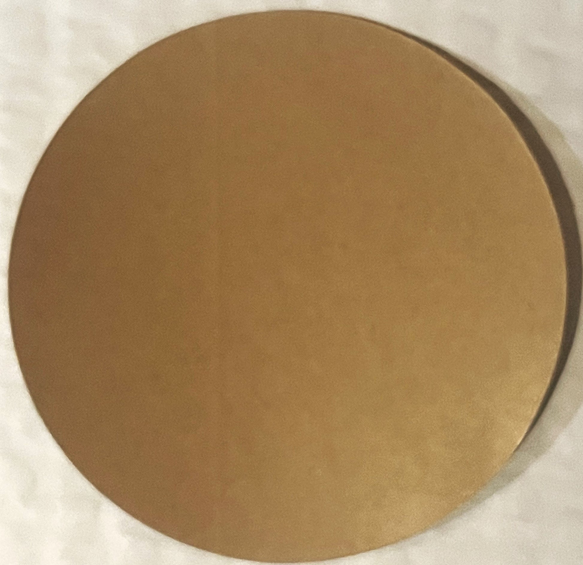 Tan circular sticker on white background, showing wear and age, mounted flat for photography
