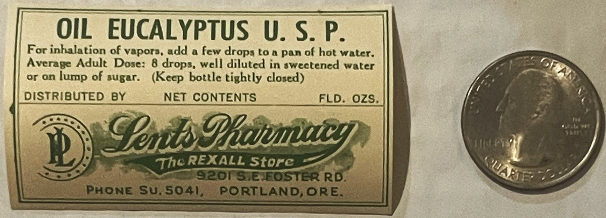 Vintage eucalyptus oil bottle label from Portland pharmacy with instructions and dosage, shown next to a quarter for scale