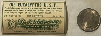 Vintage eucalyptus oil bottle label from Portland pharmacy with instructions and dosage, shown next to a quarter for scale