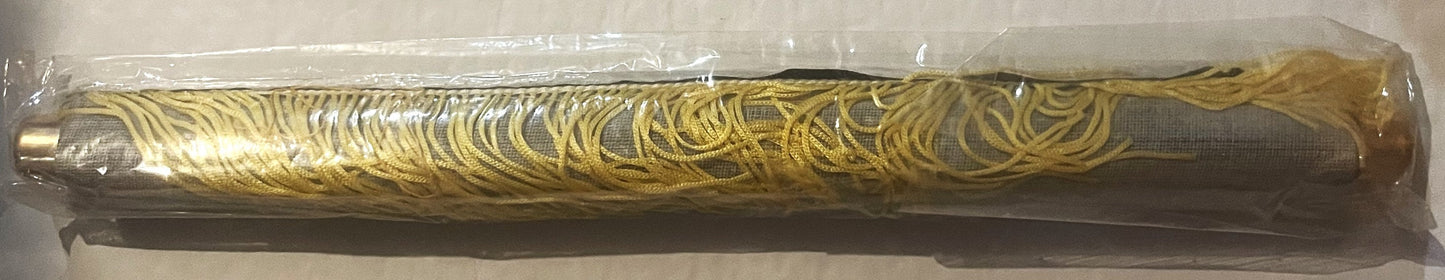 Rolled cloth calendar with gold ornamental swirl pattern on dark fabric, encased in clear plastic packaging, photographed fro
