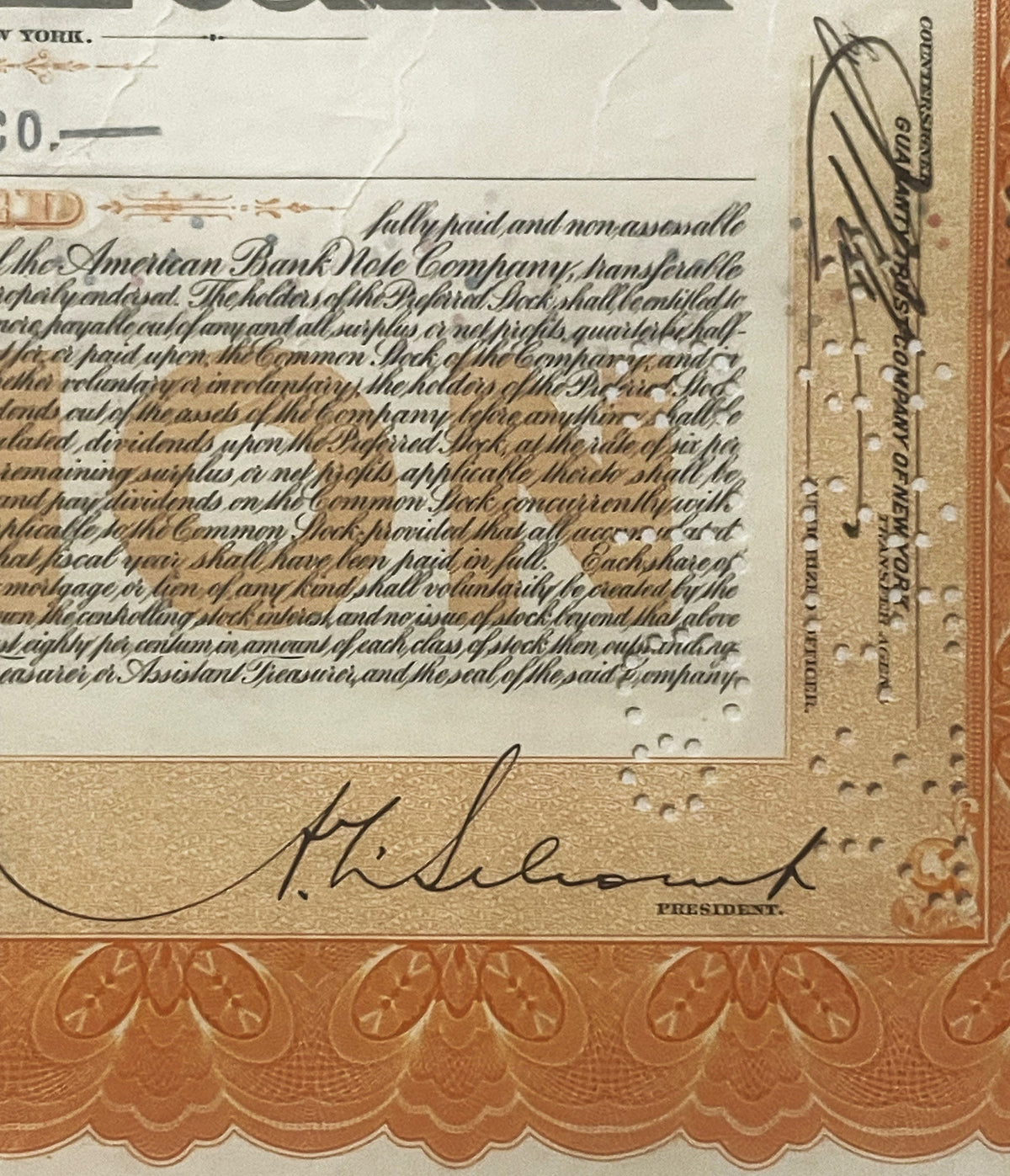 Close-up of stock certificate corner showing signature "H. Eluent" labeled "President" in cursive, ornate orange border below