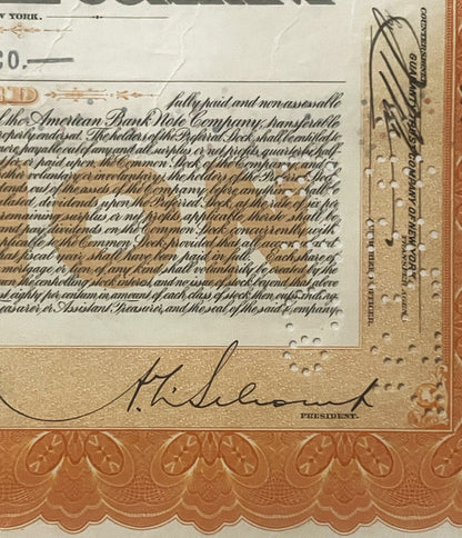 Close-up of stock certificate corner showing signature "H. Eluent" labeled "President" in cursive, ornate orange border below