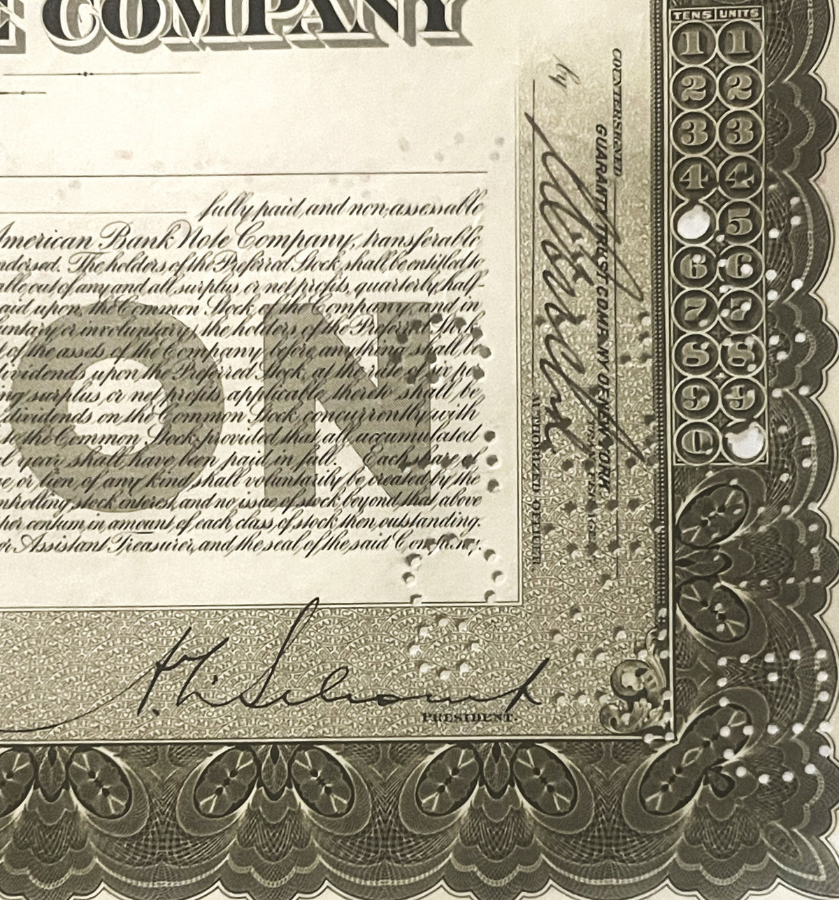 Close-up of vintage stock certificate corner showing ornate border design, numbered columns 1-11, cursive signature, and prin