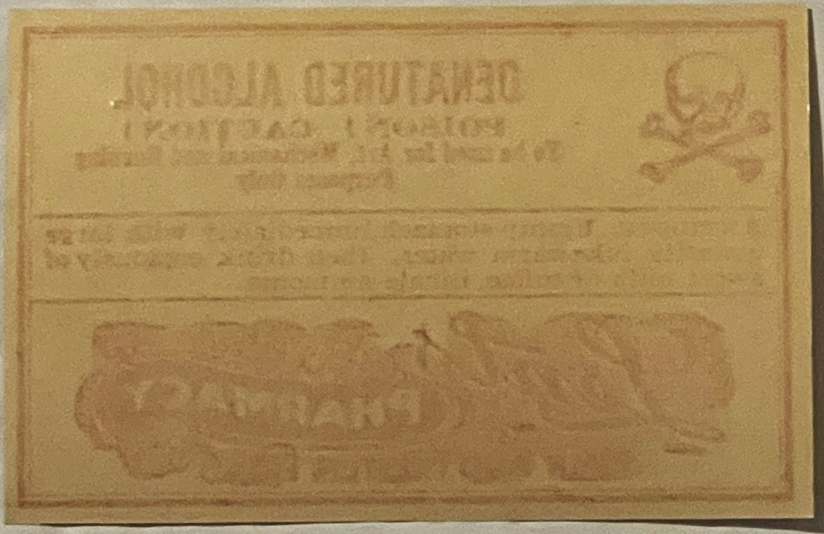 Faded tan vintage poison label with embossed text and decorative border, showing "Denatured Alcohol" and "Lents Pharmacy Port