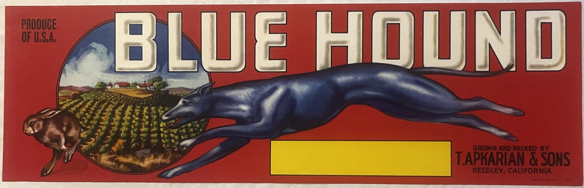 Vintage fruit crate label featuring a blue greyhound dog stretched horizontally across red background with farmland scene and