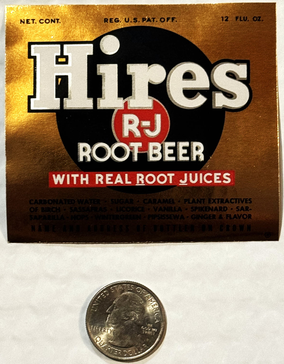 Vintage Hires R-J Root Beer label with gold background and black circle logo, shown next to quarter for scale